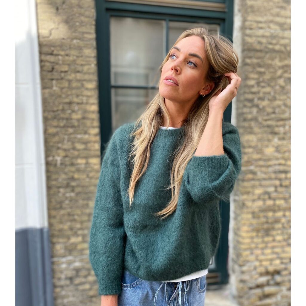 Model in een groene trui uit de collectie
